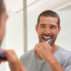 Patient in La Crosse brushing teeth to prevent dental emergencies