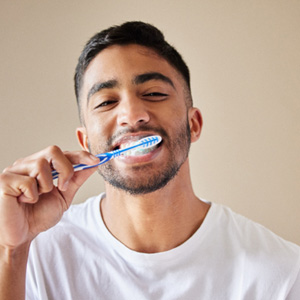 Man in white t-shirt brushing teeth