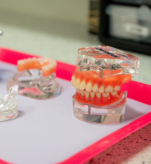 Senior dental patient looking at his smile in a mirror after replacing missing teeth in La Crosse