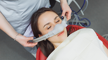 Worried woman in dental chair covering her mouth with her hands