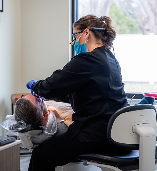 Bearded man looking at his smile in a mirror after restorative dentistry treatment