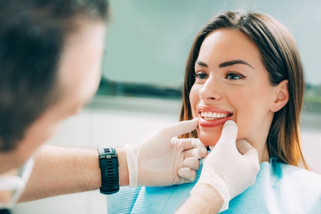 Dentist touching woman's chin with gloved hands to see her smile
